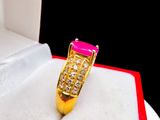 a gold ring with a pink stone in a red box