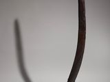 sculpture of a curved piece of metal on a stand with a shadow