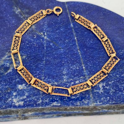 a close up of a gold bracelet on a blue stone