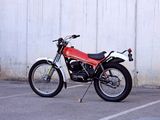 a red motorcycle parked in a parking lot next to a white wall