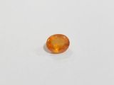 an orange sapphire stone on a white surface