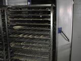 an image of a kitchen with a bunch of trays of food on a rack