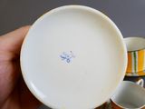 une personne tenant une tasse et une soucoupe sur lesquelles est dessiné un smiley