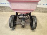 a pink spreader sitting on top of a cement floor