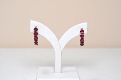 pair of red garnet stone earrings on a white stand