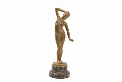 une statue en bronze représentant une femme tenant une raquette de tennis, posée sur un socle en marbre