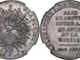a close up of a silver coin with a sun on it