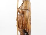an old wooden statue of a man with a staff and a hat