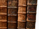 several old books are stacked on top of each other in a row