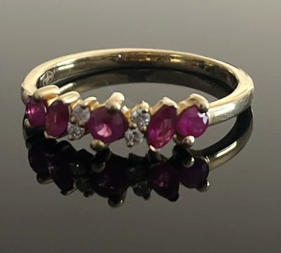 an image of a gold ring with pink stones on a black surface