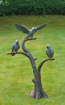 trois oiseaux étaient perchés sur une branche d'arbre dans l'herbe