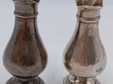 two silver salt and pepper shakers on a white surface