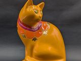 a yellow cat figurine sitting on a gray surface