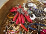 a wooden bowl filled with assorted jewelry and bracelets