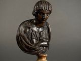 a bronze busturine of a woman holding a book