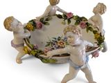 porcelain figurines of cherensils holding a bowl with flowers on it