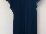 a black dress hanging on a hanger against a white wall