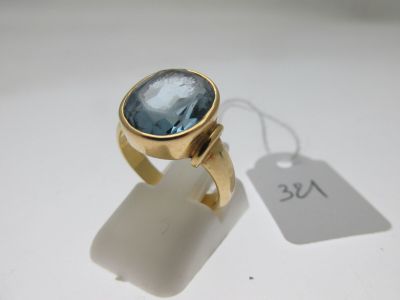 Gros plan sur une bague en or ornée d'une topaze bleue