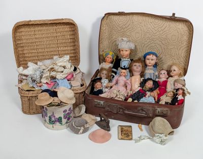a lot of dolls sitting in a suitcase on the floor