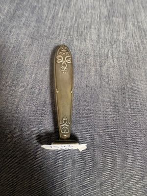 une cuillère en argent avec un manche en or posée sur un napperon gris