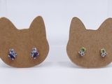 two pairs of cat shaped earrings with blue and green crystals on them
