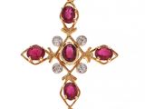 un pendentif en forme de croix, orné d'un rubis et de diamants, sur fond blanc