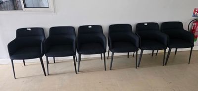 six black chairs are lined up against a wall in a room