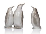 three penguins are standing next to each other on a white surface