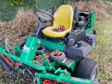une tondeuse à gazon posée dans l'herbe, à côté d'un tas de paillis