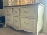 a white dresser in a room with a tv on the wall