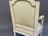 an old chair with a plaid upholstered back and a wooden frame