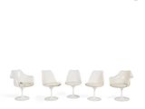 four white tulip chairs and a table in a row on a white background