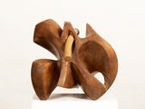 sculptures made of wood sit on a white pedestal against a white wall
