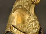 an antique gold helmet on a stand against a black background