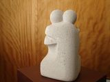 a white sculpture of a man and a woman sitting on a table
