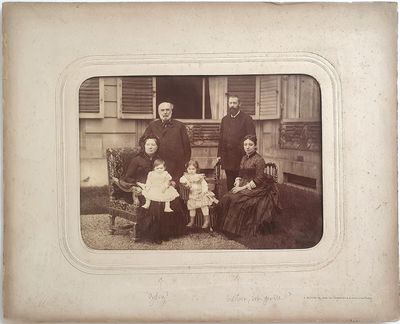 une vieille photo d'une famille posant devant une maison