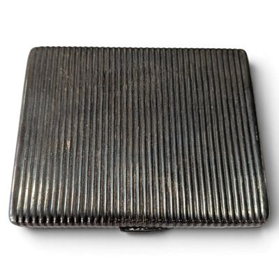 a silver cigarette case sitting on a white surface