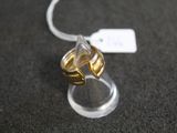 une bague en or posée sur un présentoir transparent, sur un fond noir