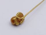 a close up of a gold flower brooch on a white surface