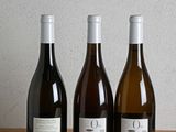 three bottles of wine are lined up on a wooden table