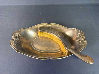 a silver plate with a brush in it on a blue surface