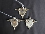 three silver metal ornaments hanging from strings on a black background