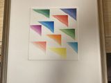 photo encadrée représentant un motif géométrique aux couleurs de l'arc-en-ciel posé sur une table en bois