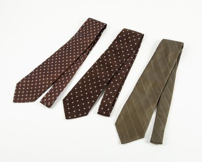 three ties on a white surface one has a brown and white polka dot pattern