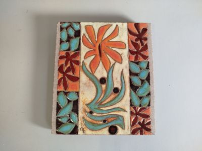 a small tile with a flower on it on a table