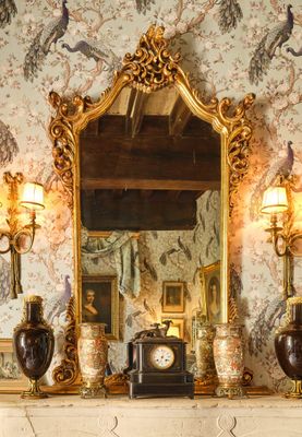 une cheminée sur laquelle sont posés un miroir et une horloge