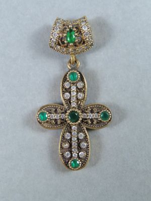 un gros plan d'une croix en forme de losange verte et blanche sur une surface blanche
