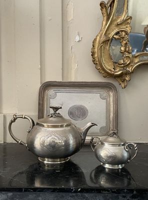 deux théières en argent posées sur une table à côté d'un miroir
