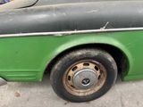 a close up of a green car with a flat tire