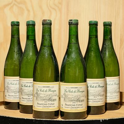 six bottles of wine are lined up on a wooden barrel